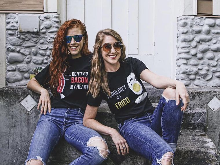 Elissa and Melissa outside in graphic tees and sunglasses